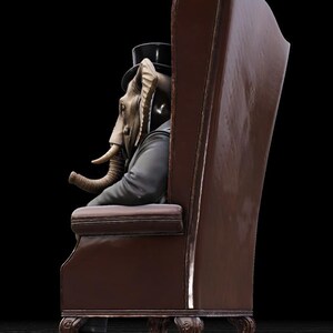 Puede incluir: Un sill&oacute;n de cuero marr&oacute;n con respaldo alto y patas ornamentadas. Sentada en el sill&oacute;n, una figura con cabeza de elefante, vestida con traje negro y sombrero de copa. La figura mira hacia la izquierda, con su trompa visible.