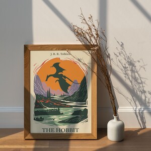 May include: A framed poster with a vintage illustration of a dragon flying over a landscape. The poster is titled "The Hobbit" and features the author's name, J.R.R. Tolkien.