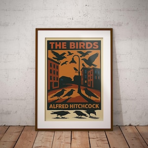 May include: A vintage-style poster for the Alfred Hitchcock film "The Birds". The poster features a black and white illustration of a city street with birds flying overhead and perched on buildings. The text "The Birds" is in red and the text "Alfred Hitchcock" is in black.