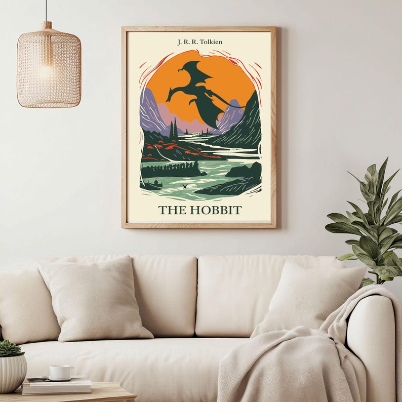 May include: A vintage-style poster for "The Hobbit" by J.R.R. Tolkien. The poster features a black silhouette of a dragon flying over a landscape with a river and mountains. The background is a sunset with orange, yellow, and purple hues.