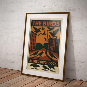 May include: A vintage-style poster for the Alfred Hitchcock film "The Birds." The poster features a black and white illustration of a city street with birds flying overhead and a streetlight in the center. The text "THE BIRDS" is in red and white, and "ALFRED HITCHCOCK" is in black.