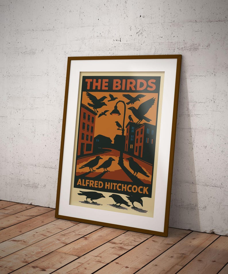 May include: A vintage-style poster for the Alfred Hitchcock film "The Birds." The poster features a black and white illustration of a city street with birds flying overhead and a streetlight in the center. The text "THE BIRDS" is in red and white, and "ALFRED HITCHCOCK" is in black.