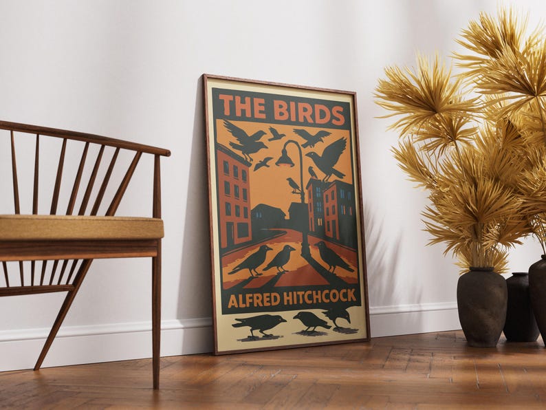 May include: A vintage-style poster for the Alfred Hitchcock film "The Birds". The poster features a black and white illustration of birds flying over a city street with buildings in the background. The text "The Birds" is in a bold, orange font and the text "Alfred Hitchcock" is in a smaller, black font.