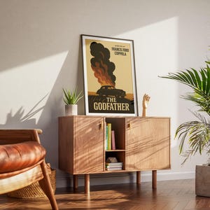 May include: A framed poster with a vintage design featuring a car engulfed in flames. The poster is titled "The Godfather" and has the director's name, Francis Ford Coppola, listed below the title.