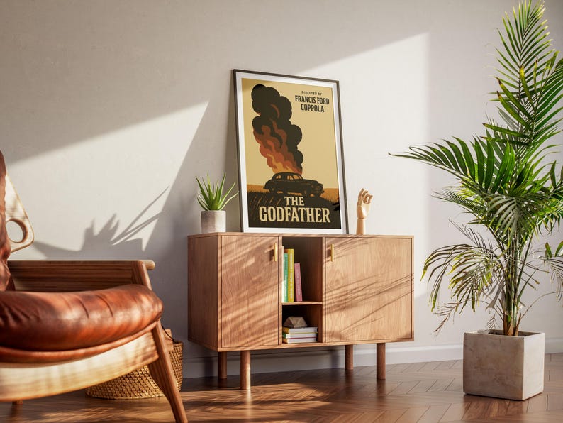 May include: A framed poster with a vintage design featuring a car engulfed in flames. The poster is titled "The Godfather" and has the director's name, Francis Ford Coppola, listed below the title.