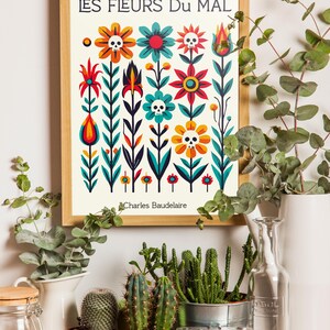 May include: A framed print with a colorful floral design featuring skulls and the text "LES FLEURS DU MAL" by Charles Baudelaire. The print is surrounded by potted plants and a camera.