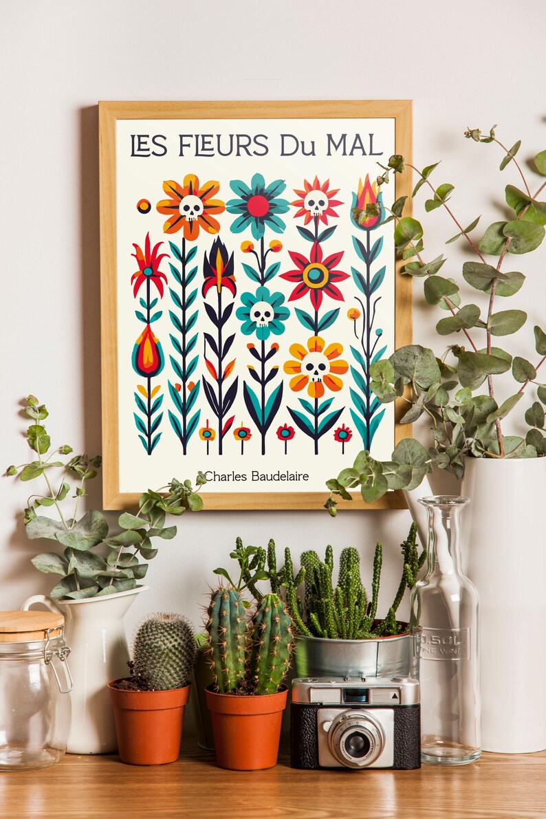 May include: A framed print with a colorful floral design featuring skulls and the text "LES FLEURS DU MAL" by Charles Baudelaire. The print is surrounded by potted plants and a camera.