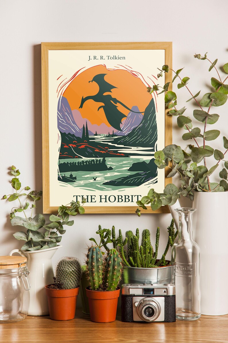 May include: A framed poster with a vintage illustration of a dragon flying over a landscape. The poster is titled "The Hobbit" and features the author's name, J.R.R. Tolkien.