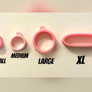 May include: Four pink silicone rings in different sizes: small, medium, large, and extra large. The rings are labelled with their sizes.
