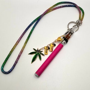 May include: A pink vape pen with a clear glass tank and a rainbow lanyard. The lanyard has charms that say "LOVE", "PEACE", and a green marijuana leaf.