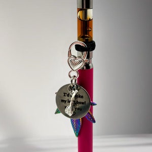 May include: A pink vape pen with a silver charm that says "I'd smoke my last bowl with you". The charm has a small heart and a leaf design.
