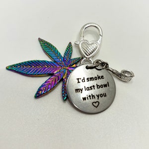 May include: A silver charm featuring a rainbow iridescent marijuana leaf, a silver heart charm, and a silver charm with the text "I'd smoke my last bowl with you" and a small heart.