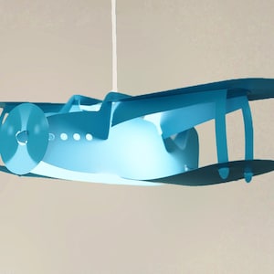May include: A blue airplane-shaped ceiling light fixture with a white cord.