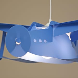 May include: A blue metal airplane shaped pendant light fixture. The light fixture has a round propeller and a white cord.