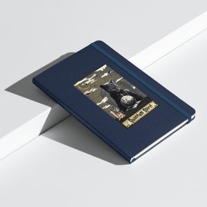 May include: A dark blue notebook featuring an illustration of a black cat and the text "Quantum Spirit".