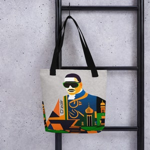 May include: A tote bag with a graphic illustration of a man wearing sunglasses and a blue and orange outfit. The bag has black handles and the word "D'zair" is printed on the side. The background is a light gray color.