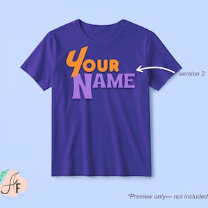 Op de afbeelding: Een paars t-shirt met korte mouwen en de tekst "YOUR NAME" op de voorkant in oranje en lichtpaarse letters. Een witte pijl wijst naar de tekst met het label "version 2" ernaast, en de tekst "Preview only&mdash;not included" staat onderaan.