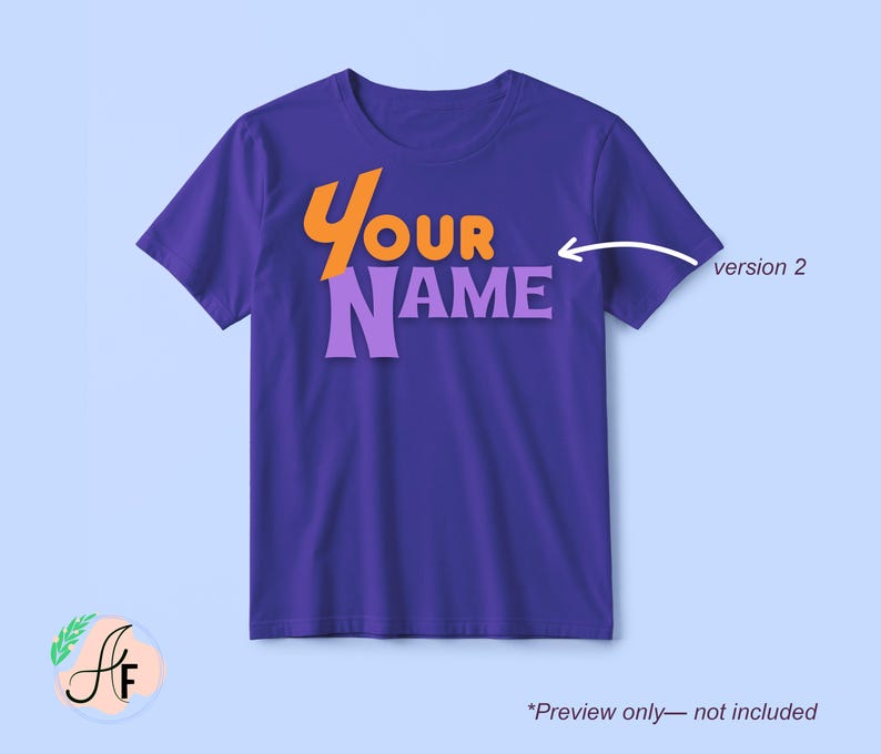 Op de afbeelding: Een paars t-shirt met korte mouwen en de tekst "YOUR NAME" op de voorkant in oranje en lichtpaarse letters. Een witte pijl wijst naar de tekst met het label "version 2" ernaast, en de tekst "Preview only&mdash;not included" staat onderaan.