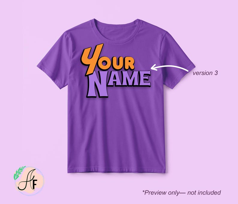 Op de afbeelding: Een paars t-shirt met korte mouwen en de tekst "YOUR NAME" in een gestileerd oranje en lichtpaars lettertype. Een witte pijl wijst naar de tekst met het label "version 3" ernaast, en de tekst "*Preview only&mdash;not included" staat onderaan.