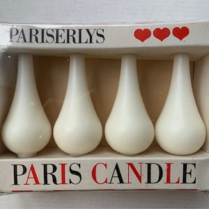 May include: A box of four white teardrop-shaped candles with the text "PARISERLYS PARIS CANDLE" on the front. The box has three red hearts on the top.