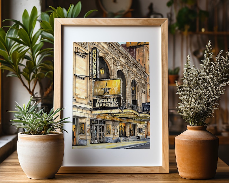 May include: A framed watercolor painting of the Richard Rodgers Theatre in New York City. The theatre is decorated with lights and signs, including the words "Hamilton" and "Richard Rodgers".
