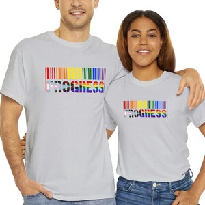 May include: Two people wearing light gray t-shirts with a rainbow barcode design and the word "PROGRESS" printed on them.