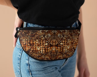 May include: A brown and black fanny pack with a crocodile skin pattern. The fanny pack is worn around the waist of a person wearing blue jeans.
