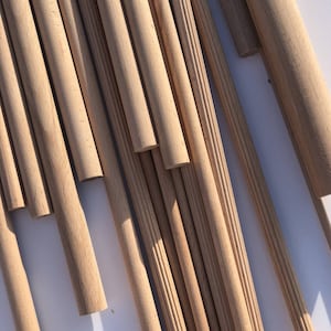 Może przedstawiać: Zbliżenie na wiązkę drewnianych kołków, niektóre gładkie, a niektóre z żłobioną fakturą. Kołki są ułożone w losowym wzorze, niektóre nakładają się na siebie.