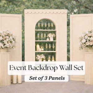 Op de afbeelding: Een crèmekleurige evenementenachtergrondwandset met drie panelen. Het middelste paneel heeft een gewelfde plank met champagneglazen, kaarsen en bloemstukken. De tekst luidt "Event Backdrop Wall Set" en "Set of 3 Panels."