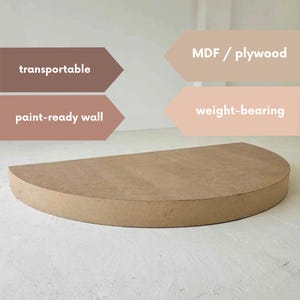 Op de afbeelding: Een halfronde wandplank van MDF/multiplex, klaar om te schilderen. De plank is lichtbruin met een platte bovenkant en een afgeronde rand. Tekst op de afbeelding geeft aan dat deze transporteerbaar en draagkrachtig is.