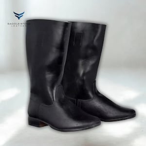 May include: A pair of black leather riding boots. The boots have a smooth, shiny finish and a traditional design, with a low heel and a tall shaft. The boots are likely made for equestrian activities.