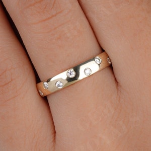 May include: A gold band ring with small round diamonds set into the band.