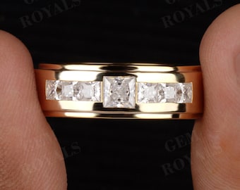 May include: A gold-colored ring with a band of square and rectangular clear stones. The ring is held between two hands against a dark background. The text "GEM ROYALS" is visible in the background.