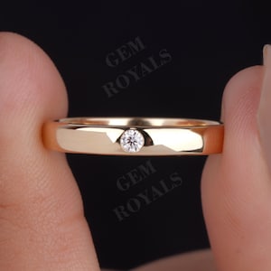 Può includere: Una fede nuziale in oro con un solo piccolo diamante rotondo incastonato al centro.