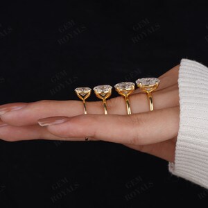 Pode incluir: Quatro an&eacute;is de ouro com diamantes de forma oval engastados em garras. Os an&eacute;is est&atilde;o dispostos em uma fila em uma m&atilde;o, com o anel maior &agrave; esquerda e o anel menor &agrave; direita.