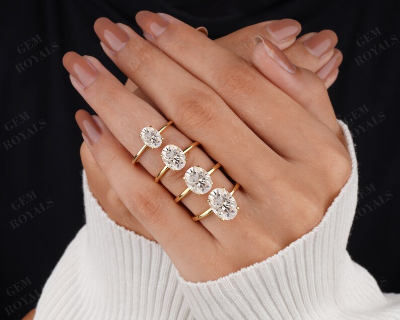 Pode incluir: Quatro an&eacute;is de ouro com diamantes de forma oval de diferentes tamanhos. Os an&eacute;is est&atilde;o empilhados em um dedo.