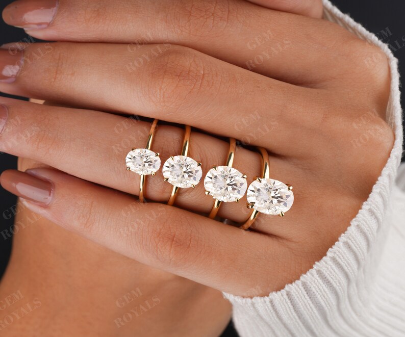 Pode incluir: Cinco an&eacute;is de ouro com diamantes de forma oval de diferentes tamanhos. Os an&eacute;is est&atilde;o empilhados uns sobre os outros, com o diamante maior na parte superior e o menor na parte inferior.