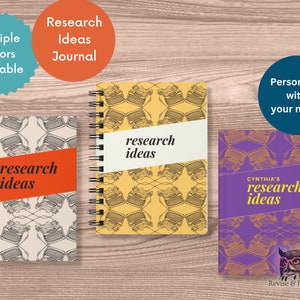 May include: Three different notebooks with a typewriter pattern and the text "research ideas" on the cover. The notebooks are in yellow, purple, and gray. The purple notebook has the name "CYNTHIA'S" on the cover. The text "Revise & Resubmit" is on the bottom of the purple notebook.