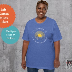 May include: A royal blue t-shirt with a graphic of a yellow sun rising over a blue ocean. The text "It's a beautiful day to write my dissertation" is printed on the shirt.