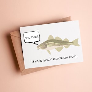 May include: A white greeting card with a cartoon codfish illustration and the text "my bad." and "This is your apology cod." The card is inside a brown envelope.