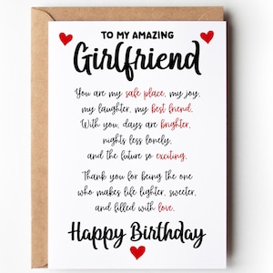 May include: A greeting card with a white front and a brown envelope. The card reads "TO MY AMAZING Girlfriend" in large black script, with a message and "Happy Birthday" below. Red heart accents are placed around the text.