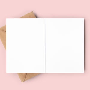 May include: A blank white card with a brown envelope. The card is folded in half and the envelope is partially covering the card.