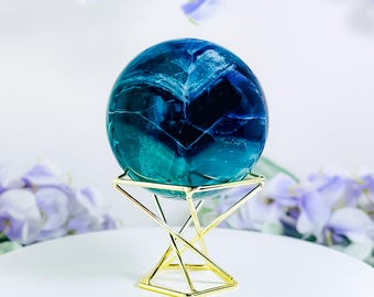 May include: A blue and green crystal sphere on a gold metal stand. The sphere has a swirling pattern of blue and green.