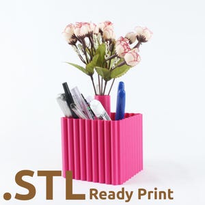 May include: A bright pink desk organizer with a ribbed design, holding pens, a phone, and a small vase of flowers. The text ".STL Ready Print" is at the bottom. The organizer is a vibrant and functional desk accessory.