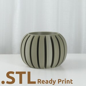 May include: A sage green, spherical planter with vertical grooves. The planter has a rounded shape and is made of a solid material. The text ".STL Ready Print" is at the bottom of the image.