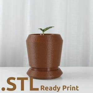 May include: A brown textured planter with a small green plant. The planter has a unique shape with a wider base and a narrower top. The text ".STL Ready Print" is at the bottom of the image.