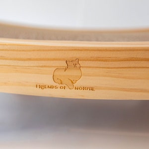 Closeup of the Friends of Normie logo engraved on the cat scratcher