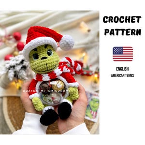 Könnte beinhalten: Eine gehäkelte Grinch-Puppe in Grün mit roter und weißer Weihnachtsmütze und Schal, die eine transparente Kugel mit Pralinen hält. Die Puppe hat schwarze Akzente und schwarze Schuhe. Der Text "CROCHET PATTERN" ist enthalten.