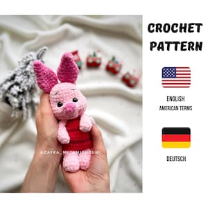 Puede incluir: Una muñeca de Piglet hecha a mano con ganchillo en tonos rosa y rojo, sostenida en las manos de una persona. La muñeca tiene grandes orejas rosas y un vestido a rayas rojas. La imagen también incluye el texto "CROCHET PATTERN" y "ENGLISH AMERICAN TERMS".