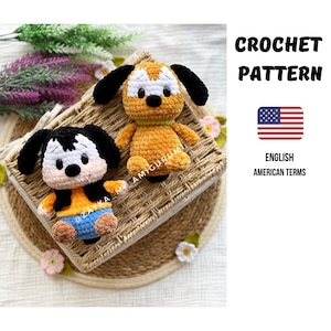 Könnte beinhalten: Zwei gehäkelte Hunde-Amigurumi-Spielzeuge sind abgebildet. Einer ist orange und weiß, der andere schwarz, weiß und orange. Sie befinden sich auf einem geflochtenen Korb. Der Text "CROCHET PATTERN" und "ENGLISH AMERICAN TERMS" ist ebenfalls im Bild enthalten.